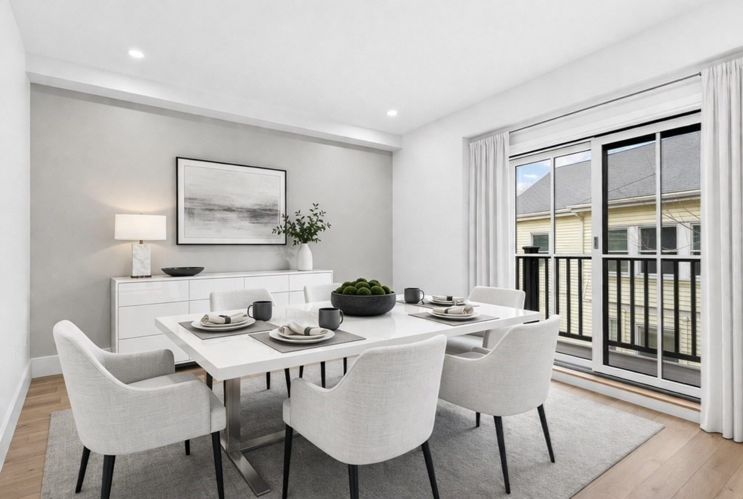 Dining area with a white table, upholstered chairs, and a sliding glass door.